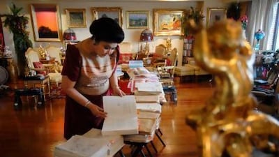 Former first lady Imelda Marcos sorts through documents of bank statements and gold certificates that she says proves the Marcos's wealth is legal.