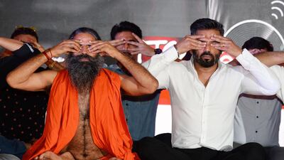 Indian yoga guru Baba Ramdev, left, has built a multibillion dollar consumer goods empire tapping into the country's preference for all-natural, wholesome products. / AFP / Sajjad HUSSAIN