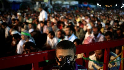 A boy wears a gas mask as supporters of Egypt's ousted President Mohammed Morsi pray in Nasr City. Hassan Ammar / AP Photo