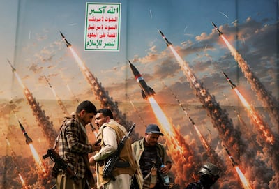 Houthi fighters, with a banner depicting missiles in the background, in Sanaa. Reuters