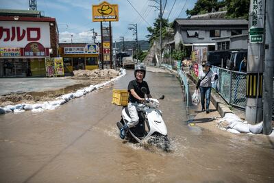 A man rides a scooter along a flooded road following a landslide. Getty Images