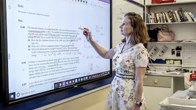 Physics teacher Regina O'Dwyer demonstrates how Dubai College's remote learning system works. Using Microsoft 365 and Cisco Webex - a Skype-style conference call tool - she can take pupils through live lessons as they sit at home. Victor Besa / The National