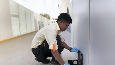 Jerwil Aguirre from Pro Shield Pest Control installs a rodent bait station trap outside a building in Dubai's Al Warqa area. Reem Mohammed / The National
