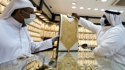 A Saudi jeweller wearing a protective face mask displays a gold necklace to a customer in Riyadh. Reuters