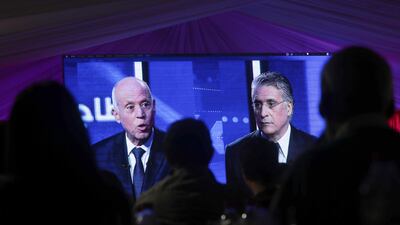 People watch a televised debate between presidential candidates Kais Saied, left, and Nabil Karoui, on the last day of campaigning before the second round of the presidential elections, in Tunis, Tunisia, Friday, October 11, 2019. AP