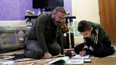 A father helps his son during online classes at home in Baghdad, Iraq. Reuters