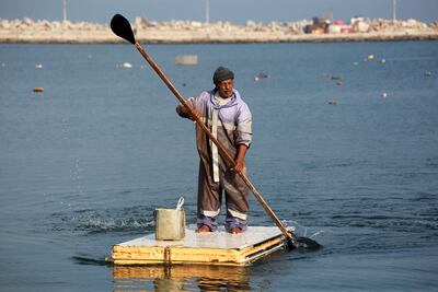 A Palestinian man uses a fridge door as a makeshift raft to fish at the port of Gaza city. AFP