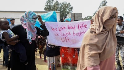 Migrants hold placards during Antonio Guterres's visit to Ain Zara detention centre for migrants. AFP