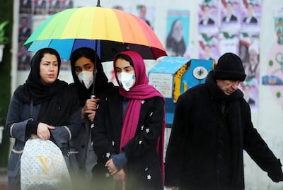 Iranian women wearing masks wait for a taxi in a street of Tehran after news broke that two people diagnosed with coronavirus died in the city of Qom EPA