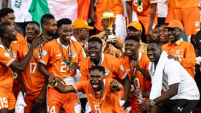 President of Ivory Coast Alassane Ouattara (C) lifts the Africa Cup of Nations trophy on the podium after Ivory Coast won the Africa Cup of Nations (CAN) 2024 final football match between Ivory Coast and Nigeria at Alassane Ouattara Olympic Stadium in Ebimpe, Abidjan on February 11, 2024. (Photo by FRANCK FIFE / AFP)