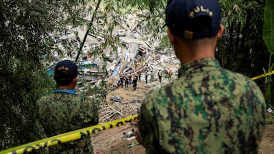 Police officers watch as workers conduct the rescue operation. Reuters