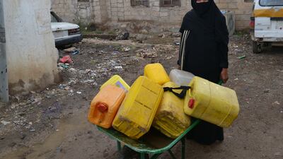 Um Ghalib goes through her daily routine of getting water for her Sanaa home, a ritual that requires queueing up for two hours. Mohammed Al Qalisi for The National