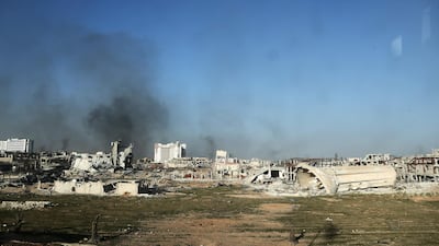 A photo taken from a bus in a convoy transporting Syrian civilians and rebel fighters shows smoke rising from destroyed buildings in Arbin in Eastern Ghouta as they are evacuated from the opposition enclave to the village of Qalaat al-Madiq, some 45 kilometres northwest of the central city of Hama, on March 25, 2018. Abdulmonam Eassa / AFP