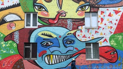 A woman walks past an apartment building with its wall covered with the graffiti by Russia's graffiti group Influx crew in the Moscow suburb. AFP