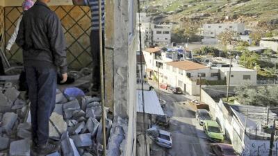 Palestinians hang national flag from the demolished apartment of Abdel Rahman Al Shaludi, who attacked a Jerusalem railway station last month. (AP /Mahmoud Illean)