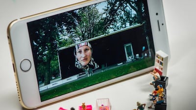 People watch a giant television screen, created by an iPhone. The other characters in the scene are doing household chores. Courtesy Omar Maree Humaid