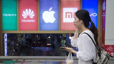 A woman using a smartphone walks past the logos of five smartphone companies outside a smartphone shop in Shenzhen. - Oppo, which started out making DVD players in the southern manufacturing hub of Dongguan over a decade ago, has exploded in popularity to become one of the top brands in China. Its market share more than doubled last year to 16.8 percent -- beating all of its competitors. AFP