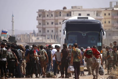 Syrian rebels and their families stand by buses to be evacuated from Deraa city, on July 15, 2018. AFP