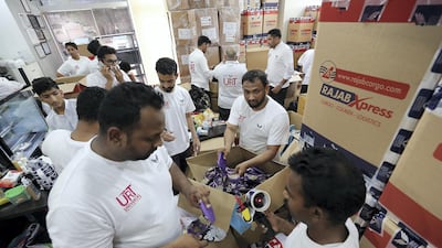 Members of the Universal Hospital Rescue Team in Abu Dhabi pack essential items such as clothing, food, medicine, blankets and baby items into aid boxes ready to be flown to Kerala flood victims. Pawan Singh / The National
