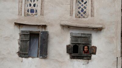 A Yemeni child peers out of a window of her family's house amid concerns over the spread of the coronavirus, in the old quarter of Sanaa, Yemen. EPA