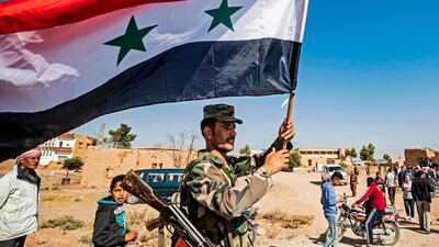 A Syrian regime soldier waves the national flag a street on the western entrance of the town of Tal Tamr in the countryside of Syria's northeastern Hasakeh province on October 14, 2019. AFP