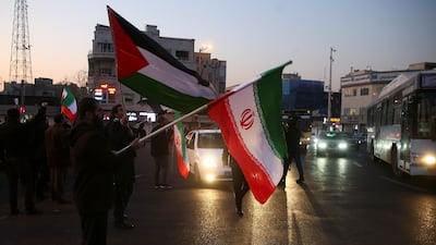 People hold Palestinian and Iranian flags as they celebrate in the street after Iran launched missiles at US-led forces in Iraq, in Tehran. Reuters