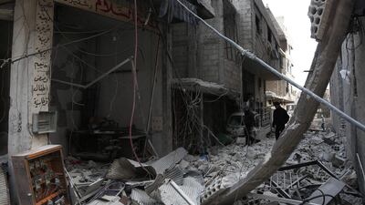 Syrians walk down a destroyed street in Arbin in the rebel-held enclave of Eastern Ghouta on February 25, 2018. Abdulmonam Eassa / AFP