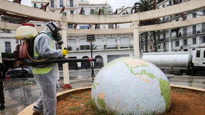 A worker wearing a protective suit disinfects a globe-shaped public garden, following the outbreak of coronavirus in Algiers, Algeria, on March 23, 2020. Reuters
