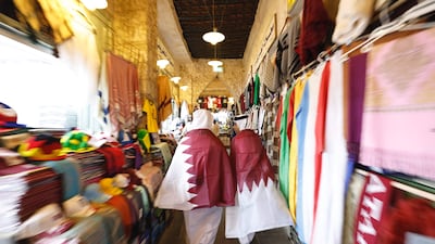 Qatari youths wearing their national flags walk in Souq Waqif marketplace in Doha. AFP