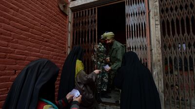 An Indian policeman checks voter cards of Kashmiri women before they cast their ballots at a polling station in Bijbehara, south of Srinagar on April 24. AFP PHOTO / Tauseef MUSTAFA