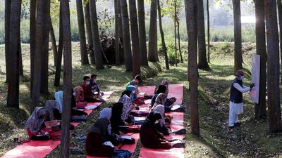 Students wearing protective face masks attend their class under the trees as they maintain social distancing outside their school in Gund on the outskirts of Srinagar. Reuters