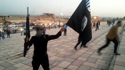 A fighter of ISIL holds the insurgents' flag and a weapon on a street in the city of Mosul, Iraq, June 23, 2014. Stringer /Reuters Photo