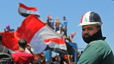 An Iraqi protester looks on as others wave national flags during an anti-government demonstration on Al Jumhuriyah bridge in the capital Baghdad. AFP