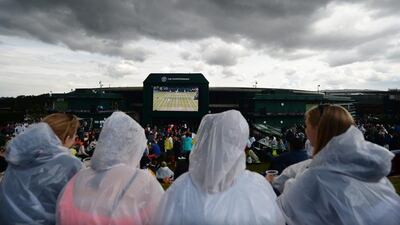 Spectators take shelter from rain showers on the sixth day of the 2014 Wimbledon Championships at the All England Club on Saturday. Andy Rain / EPA