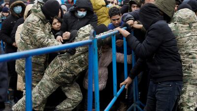 Belarusian servicemen hold a barrier as migrants jostle to receive food outside the transport and logistics centre near the border in the Grodno region. Reuters