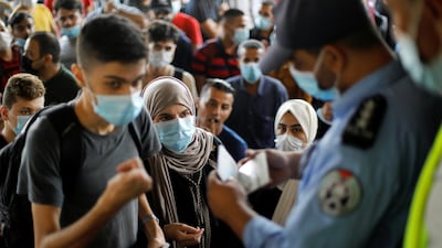 People wearing protective face masks have their documents checked by a police officer as they wait to leave the Palestinian Rafah border crossing with Egypt in the southern Gaza Strip. Reuters