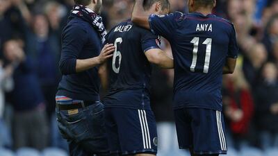 Shaun Maloney is congratulated by a teammate and a fan who came onto the pitch for helping create Georgia's own goal in Scotland's 1-0 win on Saturday in Euro qualifying in Glasgow. Russell Cheyne / Reuters / October 11, 2014