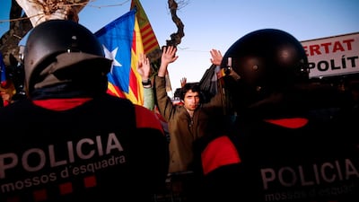 Demonstrators raise their hands as they stand in front of Catalan regional police during a demonstration outside the Catalan parliament. AFP/Pau Barrena
