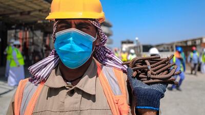 A worker wearing a safety helmet, face mask and gloves at the construction site. Victor Besa / The National