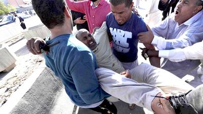 People carry a man who was injured when Libyan militiamen opened fire into a crowd of protesters in Tripoli on Friday. At least four more people were killed on Saturday as fighting in the Libyan capital continued. Reuters