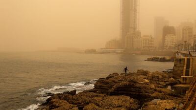 A man walks on the rocky coastal area along the Beirut coastline during a sandstorm. Hassan Ammar / AP Photo