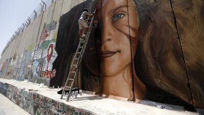 An Italian artist paints a mural of Palestinian Ahed Tamimi on the Israeli separation wall in the West Bank city of Bethlehem. EPA