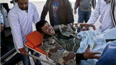 Doctors carry an injured rebel into an ambulance in Brega, Libya, yesterday. Many rebels were angry at international inaction.