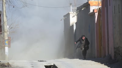 An Afghan man runs away as dust blows in the aftermath of the third blast in the Afghan capital. Shah Marai / AFP Photo