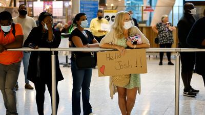 A mother holds a sign for her son as she waits for him at Terminal 5. AFP
