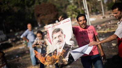 Egyptians against ousted President Mohammed Morsi burn his poster amid charred debris of the Nahda sit-in camp. Manu Brabo / AP Photo