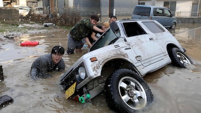 Residents try to right a submerged car after heavy rains caused flooding in Kurashiki, Okayama Prefecture, Japan. Jiji Press / EPA