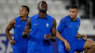 Jules Kounde and Kylian Mbappe stretch during a training session. AP