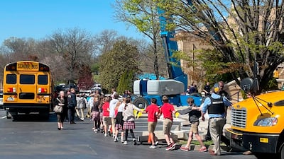 Pupils hold hands as they are taken to the church after the shooting. AP