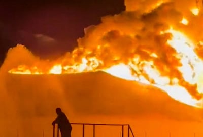 A fire in a storage tank burns as firefighters work to control the blaze at an oil refinery in Zawiya. Reuters